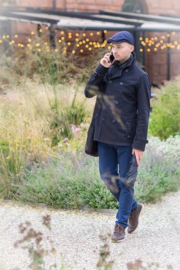 Genç bir adam telefonuyla arama yapıyor ve dışarı çıkıyor. 