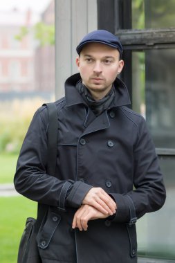 Genç bir adam parkta duruyor ve bir randevu bekliyor.