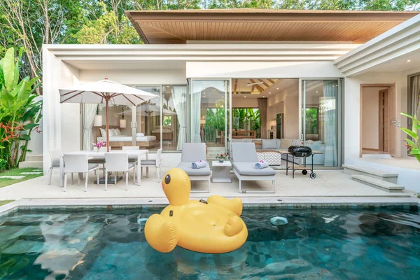 Casa o casa de diseño exterior que muestra villa piscina tropical con jardín verde, tumbonas y pato flotante —  Fotos de Stock