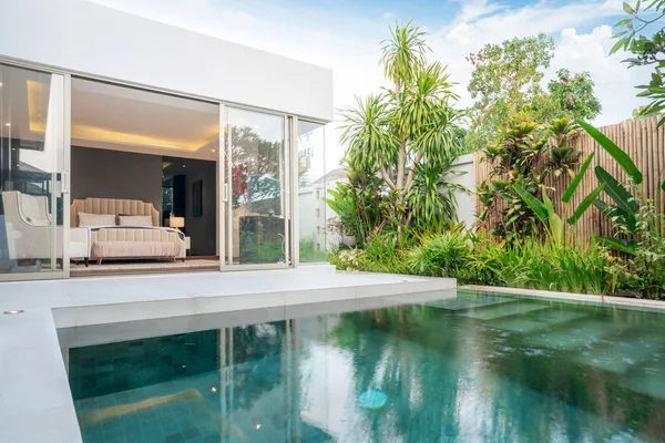 Внешнее и внутреннее оформление виллы с тропическим бассейном и зеленым садом и спальней — стоковое фото