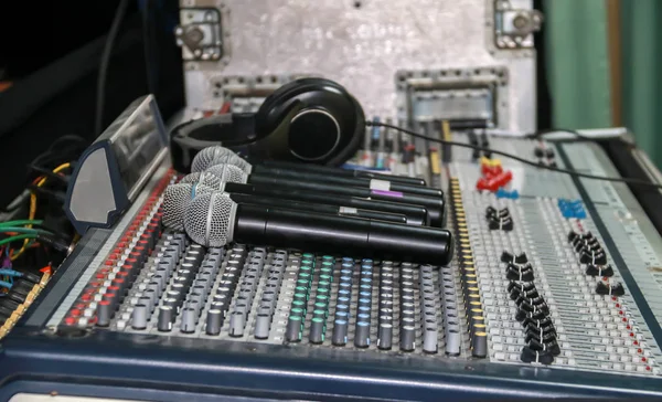 Primer plano del micrófono inalámbrico y auriculares puestos en el panel de control del mezclador de música de sonido. Panel de ecualizador del mezclador de sonido — Foto de Stock