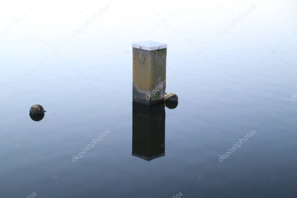 Mooring post reflecting in river Rotte at the Rottemeren in Zevenhuizen in the Netherlands