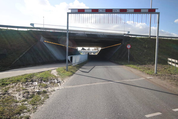 Тоннель на Noordelijke Dwarsweg с высотой барьера, чтобы предупредить слишком высокие грузовики в Zevenhuizen в Нидерландах
