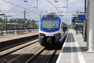 Hollanda 'daki Lage Zwaluwe tren istasyonunda NS platformu boyunca flört eden bir stadlar sprinter.