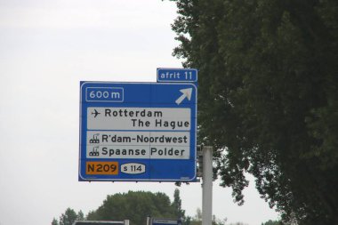 Rotterdam 'a yönelen mavi-beyaz yol işareti Lahey Havalimanı ve A13 otobanındaki sanayi bölgeleri