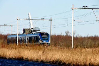 NS 'den CAF Civity sprinter treni Noordwijkerhout' ta yel değirmeni boyunca ilerliyor.