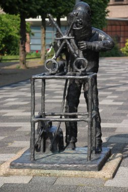 Hollanda 'daki Waddinxveen belediyesinin arması, iki anahtar taşıyan dökme demirdeki demircinin heykeli.