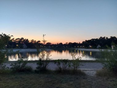 Açık gökyüzü ile gün batımı Hollanda 'daki Veluwe' de bir gölde Loo 'da karaya vurmuş.