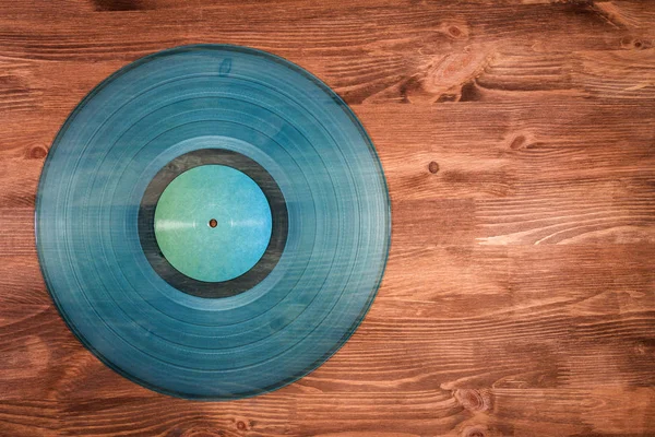 茶色の木製の背景のシアンの透明なビニール レコード — ストック写真