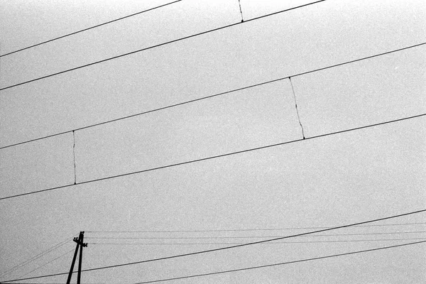 粒子の粗いフィルム質感の空と電線線を抽象化します 最小限の通りの写真撮影 黒と白のフィルム 不機嫌な空映画の背景 — ストック写真
