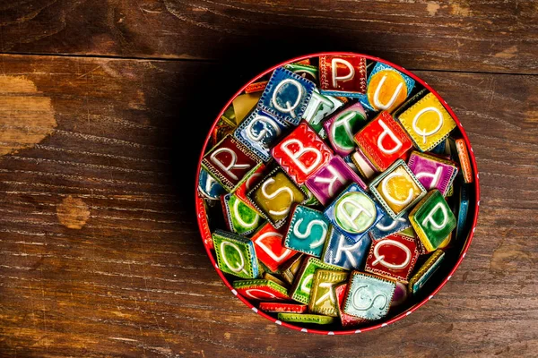 Lata llena de baldosas de cerámica de colores con letras — Foto de Stock