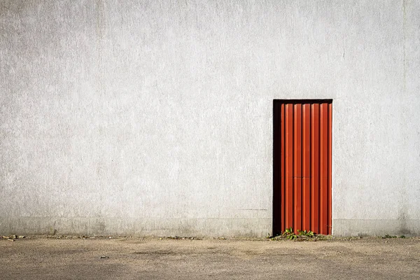 Красная дверь посреди серой бетонной стены — стоковое фото