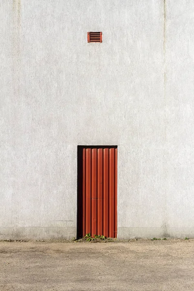 Czerwone drzwi w środku szarej ściany betonowej — Zdjęcie stockowe