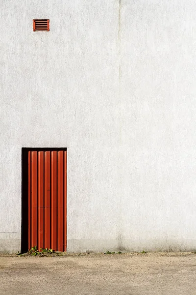 Gri beton duvarın ortasında kırmızı kapı — Stok fotoğraf