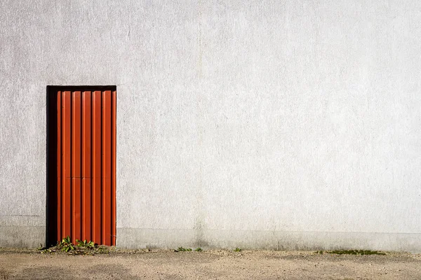 Porta rossa nel mezzo di un muro di cemento grigio — Foto Stock