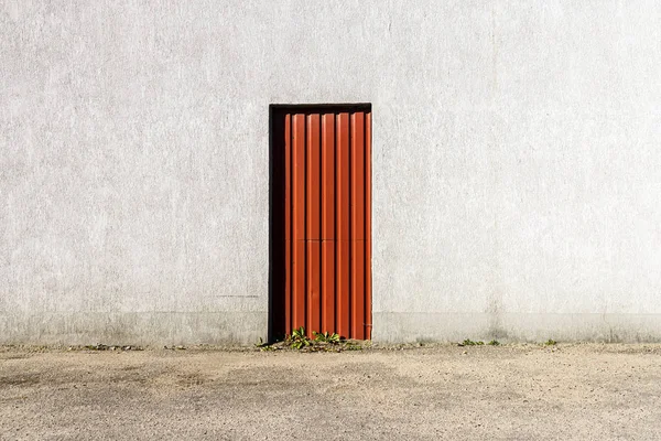 Porta vermelha no meio de uma parede de concreto cinza — Fotografia de Stock