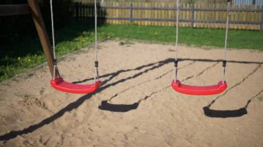 Bir çocuk playgroundslow hareketle rüzgarda sallanan bir çocuk oyun alanı rüzgarda sallanan iki boş kırmızı Çocuk salıncaklar video Çocuk salıncaklar