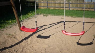 Çocuk ve geriye bir çocuk oyun alanı içinde ileri geri hareket iki boş kırmızı Çocuk salıncaklar bir çocuk playgroundslow hareket video hareketli salıncaklar