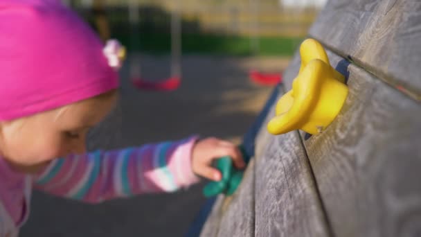 女の子 赤ちゃんの子供の遊び場 クライミングウォールを登る子供 Playgroundvideo で壁を登る子供のホールド グリップ 登山のクローズ アップ — ストック動画