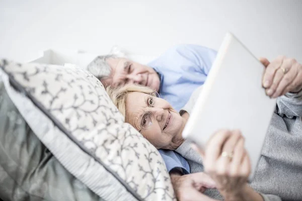 Äldre Par Liggande Sängen Och Titta Digitala Tablett — Stockfoto