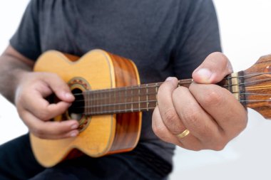 Genç adam ukulele gömlek ve siyah pantolon ile beyaz arka plan üzerinde oynama