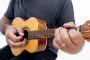 Genç adam ukulele gömlek ve siyah pantolon ile beyaz arka plan üzerinde oynama