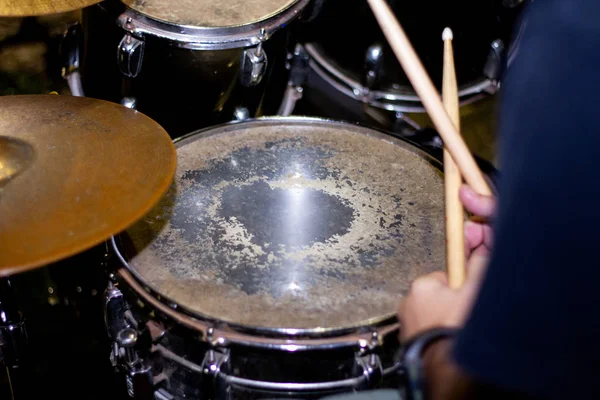 Hands of drummer with sticks and drums close-up on dark