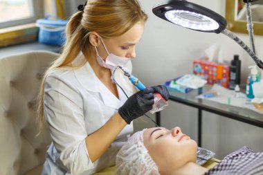 Microblading kaşlar iş akışında bir güzellik salonu. Renkli ona göz kaşları olan kadın. Kaşları için yarı kalıcı makyaj. Modelleri yüz ve kaş odaklanmak