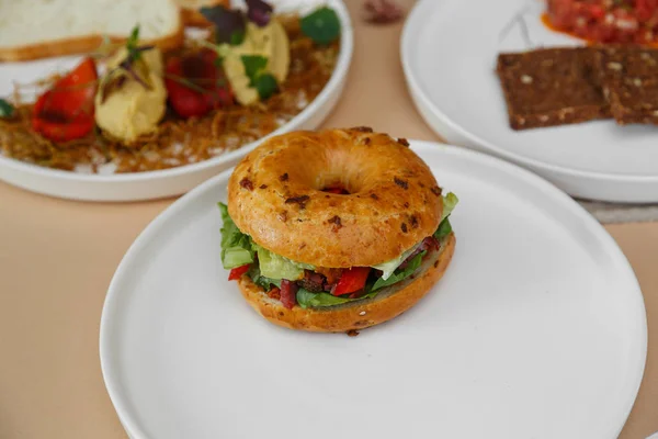 Bagels com creme, abacate, salmão, tomates em tábua de madeira e fundo bege mesa. Comida saudável café da manhã — Fotografia de Stock