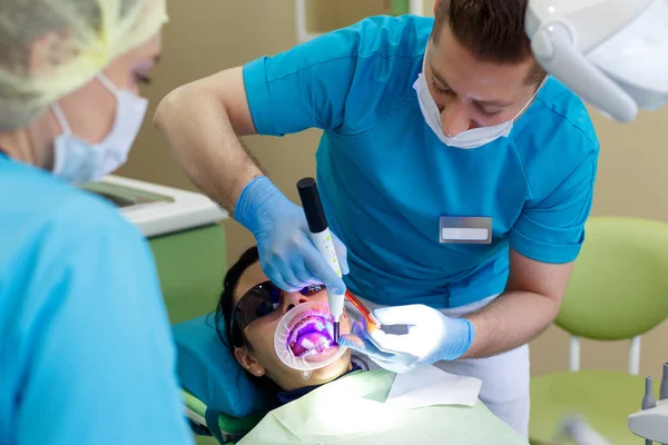 Dentista en el trabajo en la unidad dental con una enfermera y una mujer que miente paciente . —  Fotos de Stock