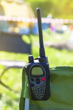 Taşınabilir bir telsiz bir turist sandalyenin arkasında asılı. Yaz, doğa.