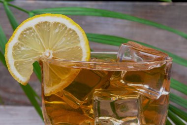 Limonata eğreltiotu şube yalan buz küpleri arka planı yanında limonlu bir bardak içinde.