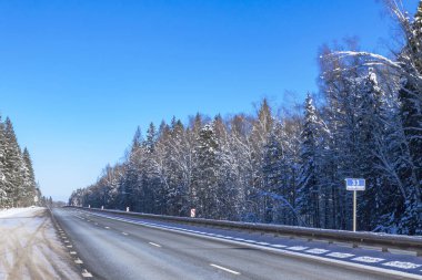 Bir kış gününde orman yolu. Ağaçlarda kar bir sürü.