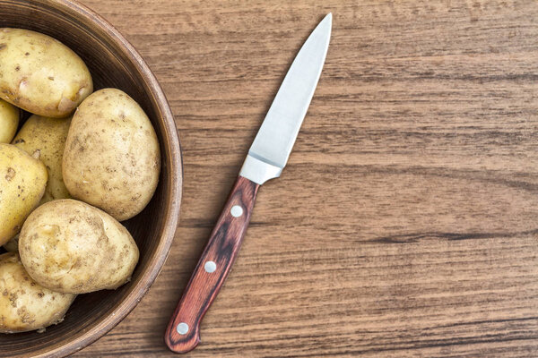 Сырой картофель в глиняной миске, крупным планом
.