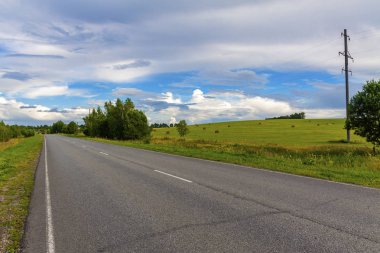 Asfalt yolu tarlalar ve ormanlar arasındaki mesafeye gidiyor.
