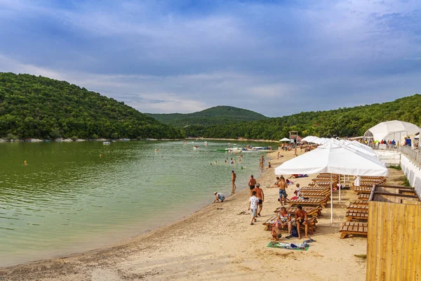 Anapa, Rusya, 24.07.2019 Kumlu plajda mavi gökyüzünün arka planında bir araba ve tatilciler var. — Stok fotoğraf