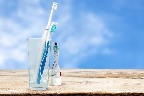 Gökyüzü arka planında mekanik ve elektrikli diş fırçaları.