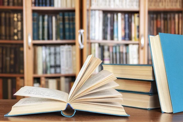 Kitaplar kitaplıkların arka planına karşı masanın üzerinde yatıyor.