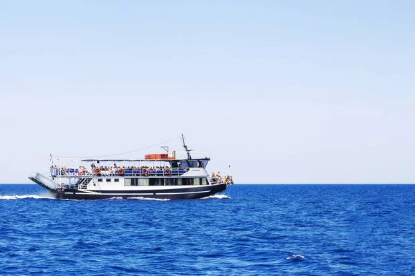 Potěšení loď s lidmi na moři, proti modré obloze. — Stock fotografie