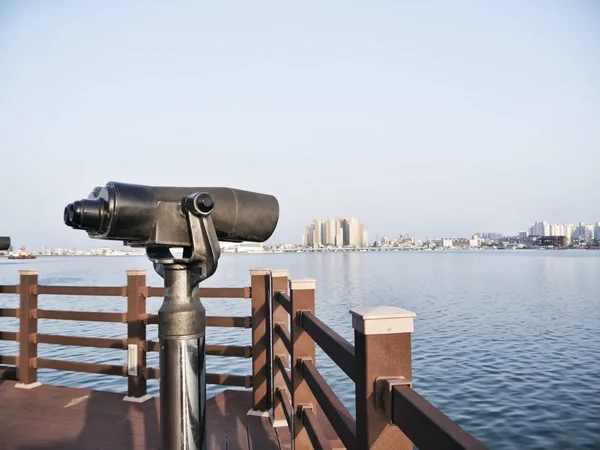 Observation binoculars on the pier and Sokcho city on the background, South Korea