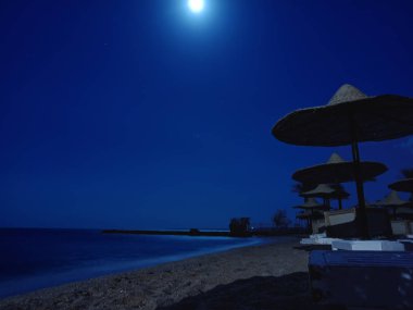 Akşam ile hasır şemsiyeleri sahilde. Hurghada, Mısır