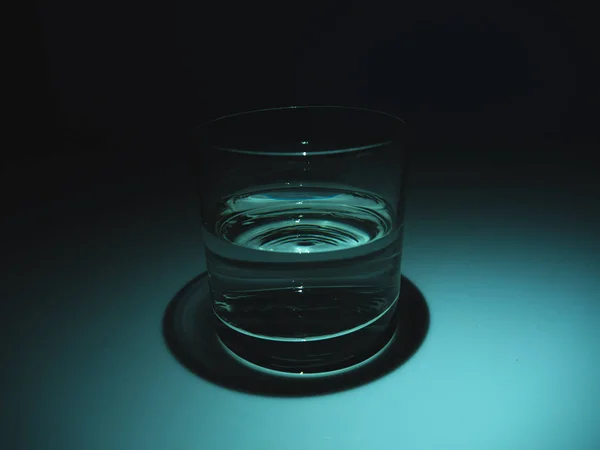 Setengah gelas penuh dengan air di kegelapan. Latar belakang hitam — Stok Foto