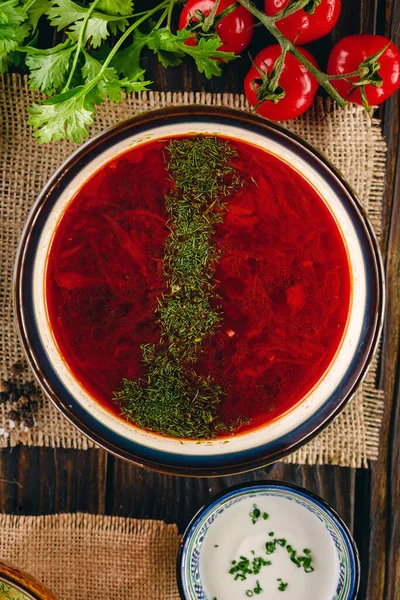 Red borsch served on the linen napkin surrounded with vegetables — Stock Photo, Image