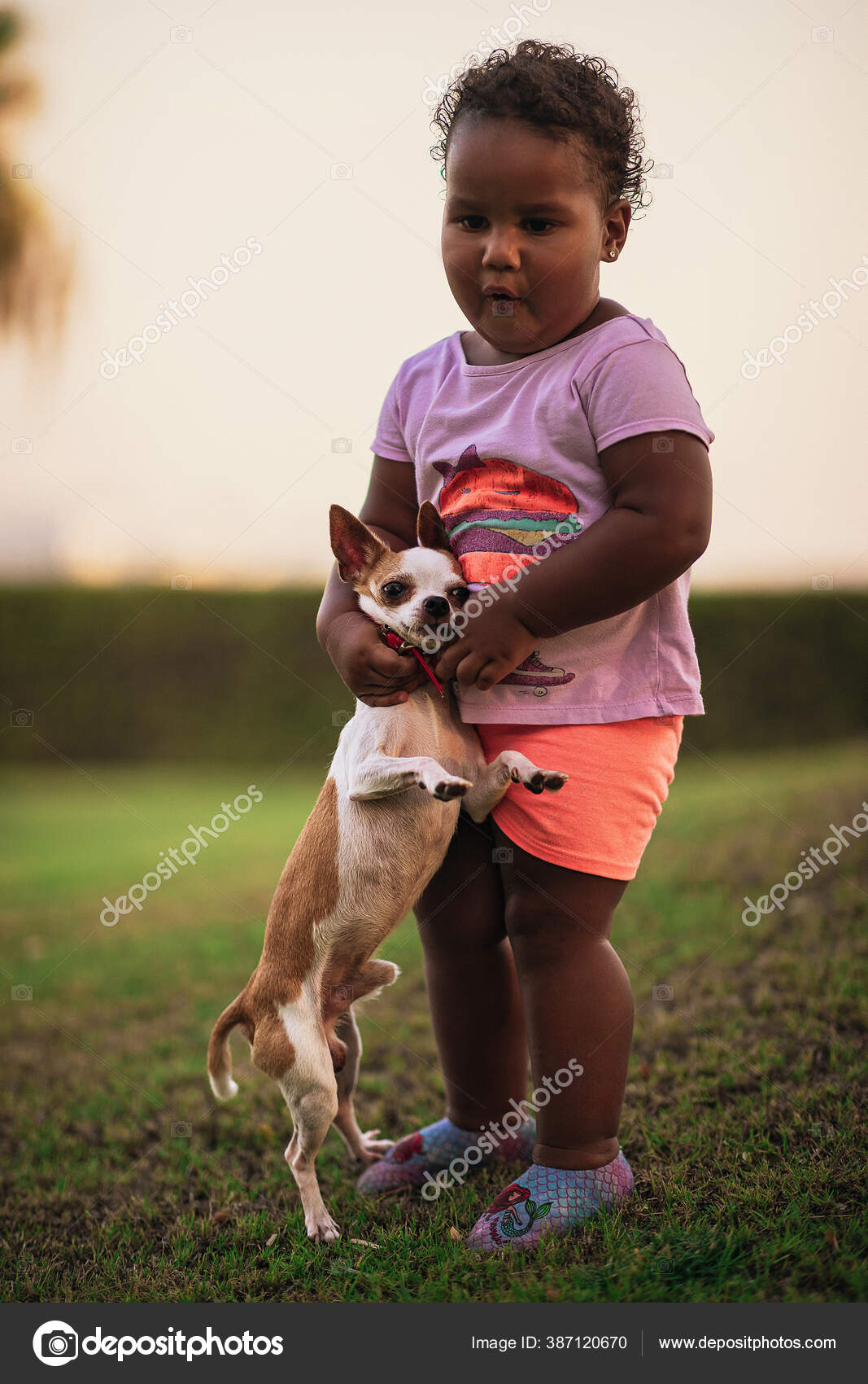 Cute little african american kid holds and hugs her dog in a funny