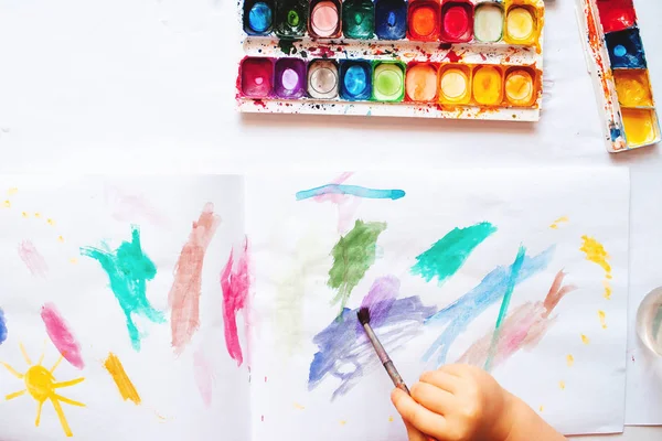The child draws with watercolor paints