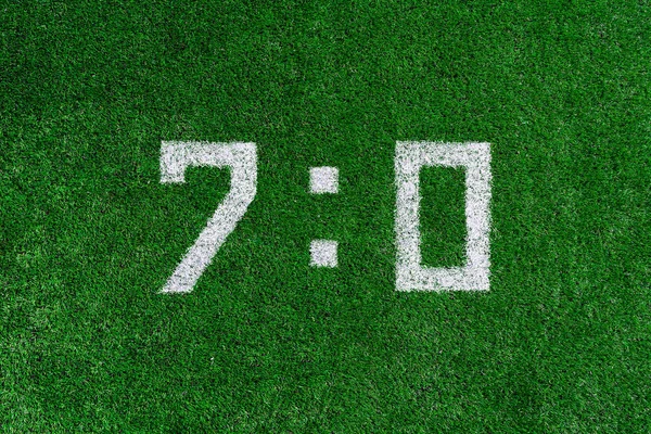 Football score.White numbers seven and zero are drawn on the green grass,creative scoreboard