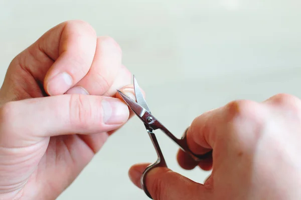 A man cuts a nail on his little finger.Hands holding nail scissors, close-up
