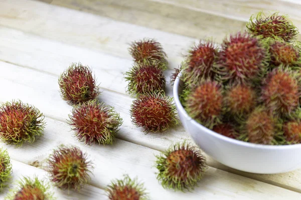 Rambutan fresco in soffio bianco e qualche goccia sul tavolo di legno. Focus morbido e attenzione al rambutan sul tavolo in legno — Foto Stock