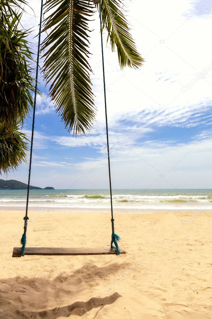 Summer concept. Wood swing hanging from coconut palm tree over beach sea. Asia Thailand. with copy space for text or design