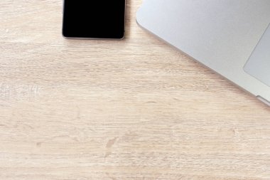 ahşap masada dizüstü bilgisayar ve akıllı telefon